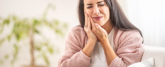 Woman holding her jaw in visible pain and discomfort