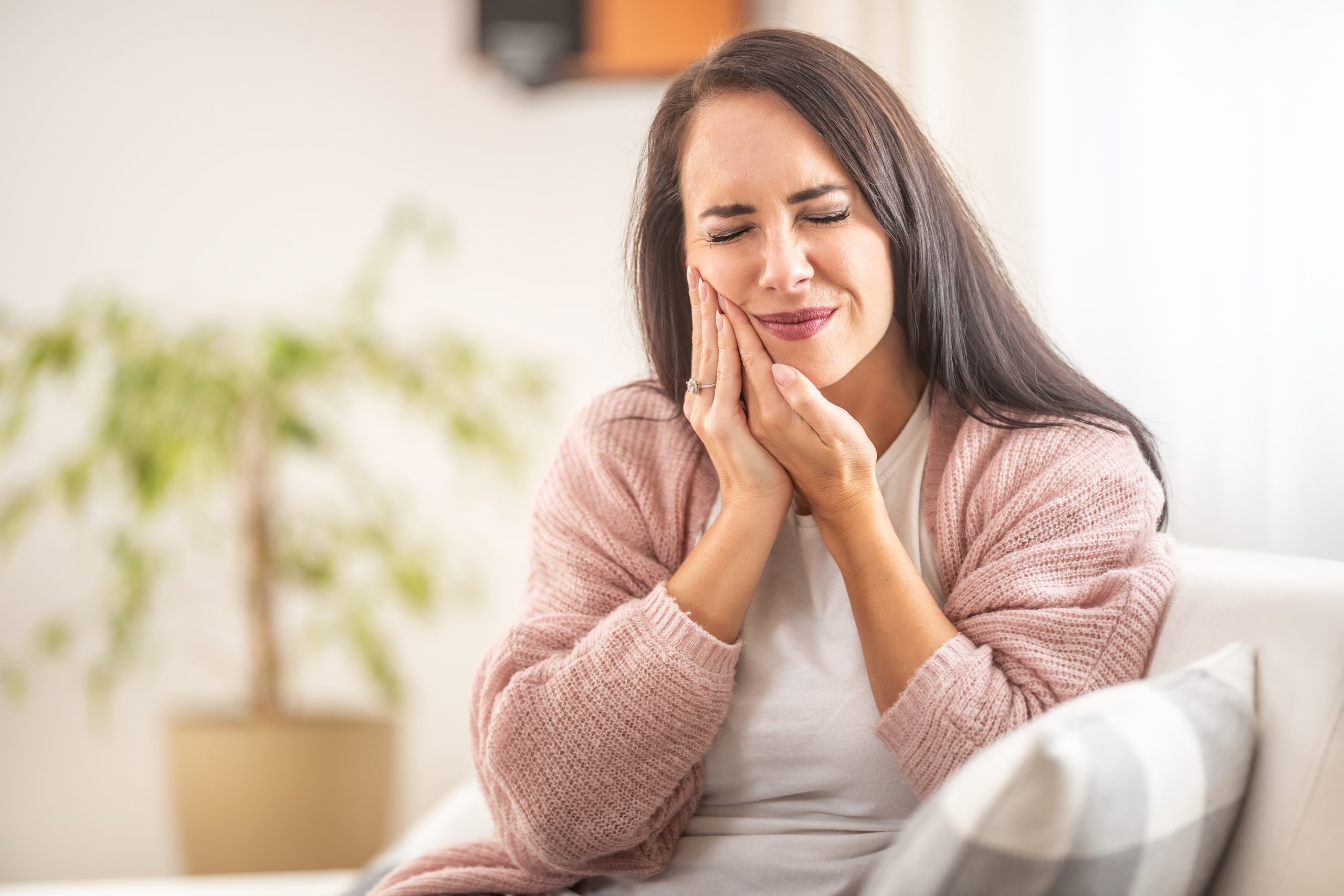 Woman holding her jaw in visible pain and discomfort
